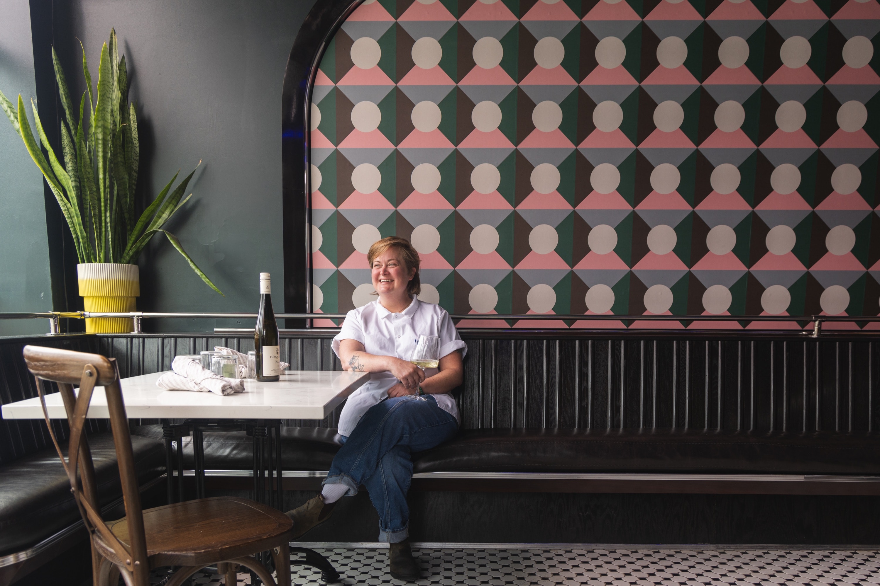 Erin Ellis at a table at Stumble Out, a bottle of wine beside her